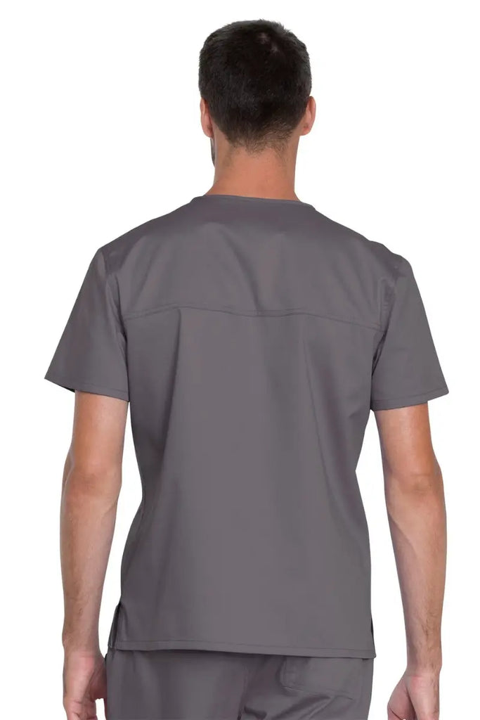 A young male Pharmacy Technician wearing a Pewter Dickies Industrial Unisex Scrub Top in size XL featuring a back yoke and center back length of 29" to provide a professional all day look.