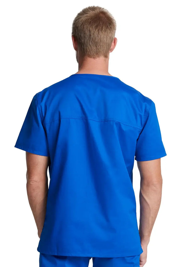 A young male Physical Therapist showcasing the back of the Dickies Industrial Unisex Tuckable V-Neck Scrub Top in size 3XL featuring a center back length of 29" to allow for a neat and professional tuck-in.