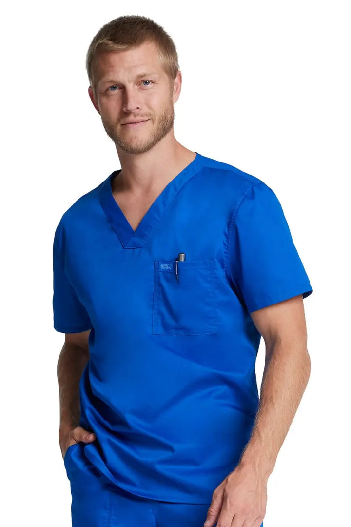 A young male Doctor wearing a Dickies Industrial Unisex Tuckable Scrub Top in Royal Blue featuring a v-neckline and short sleeves.