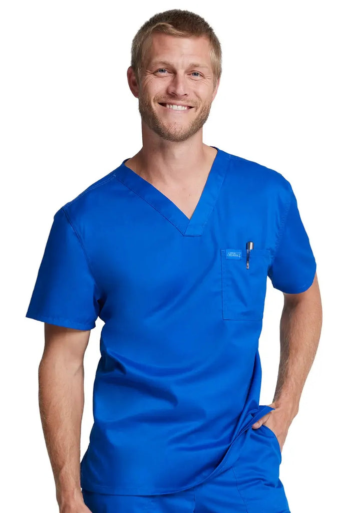 A young male Physician wearing a Royal Blue Dickies Industrial Unisex Tuckable V-Neck Scrub Top in size XXS featuring one conveniently placed chest pocket. 