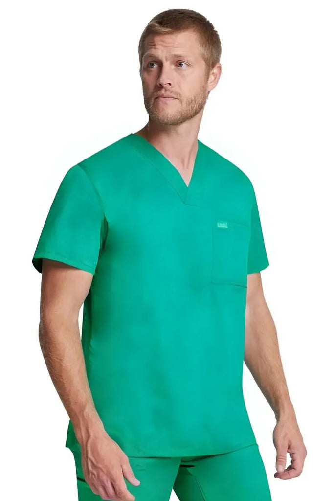 A young male Surgeon wearing a Dickies Industrial Unisex Tuckable V-Neck Scrub Top in Surgical Green size 2XL featuring side vents to provide enhanced breathability.