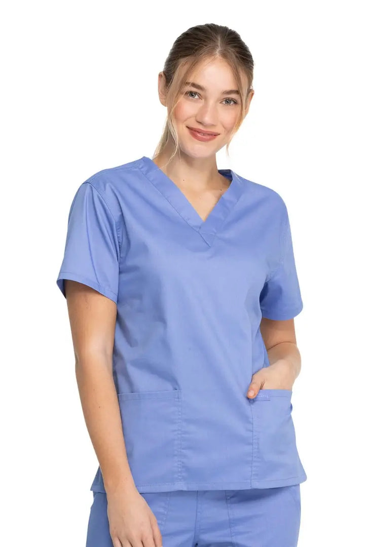 A young female Medical Student wearing a Dickies Industrial Unisex V-Neck Scrub Top in Ceil Blue size XXS featuring short sleeves.