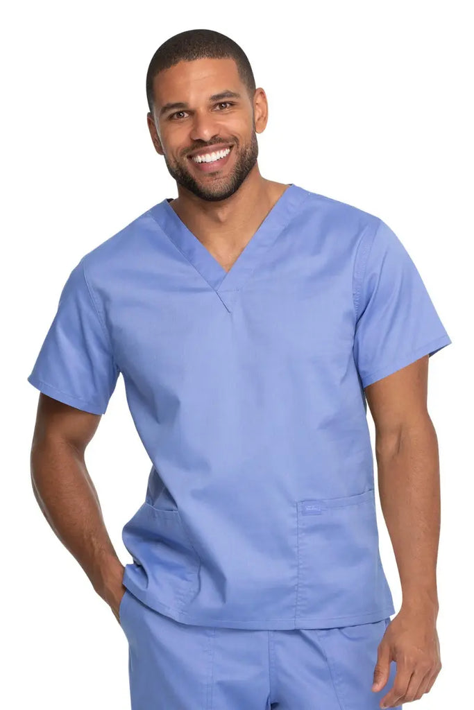 A young male Nurse Practitioner wearing a Dickies Industrial Unisex V-Neck Scrub Top in Ceil Blue size 5XL featuring a soft and breathable fabric that offers all-day comfort.