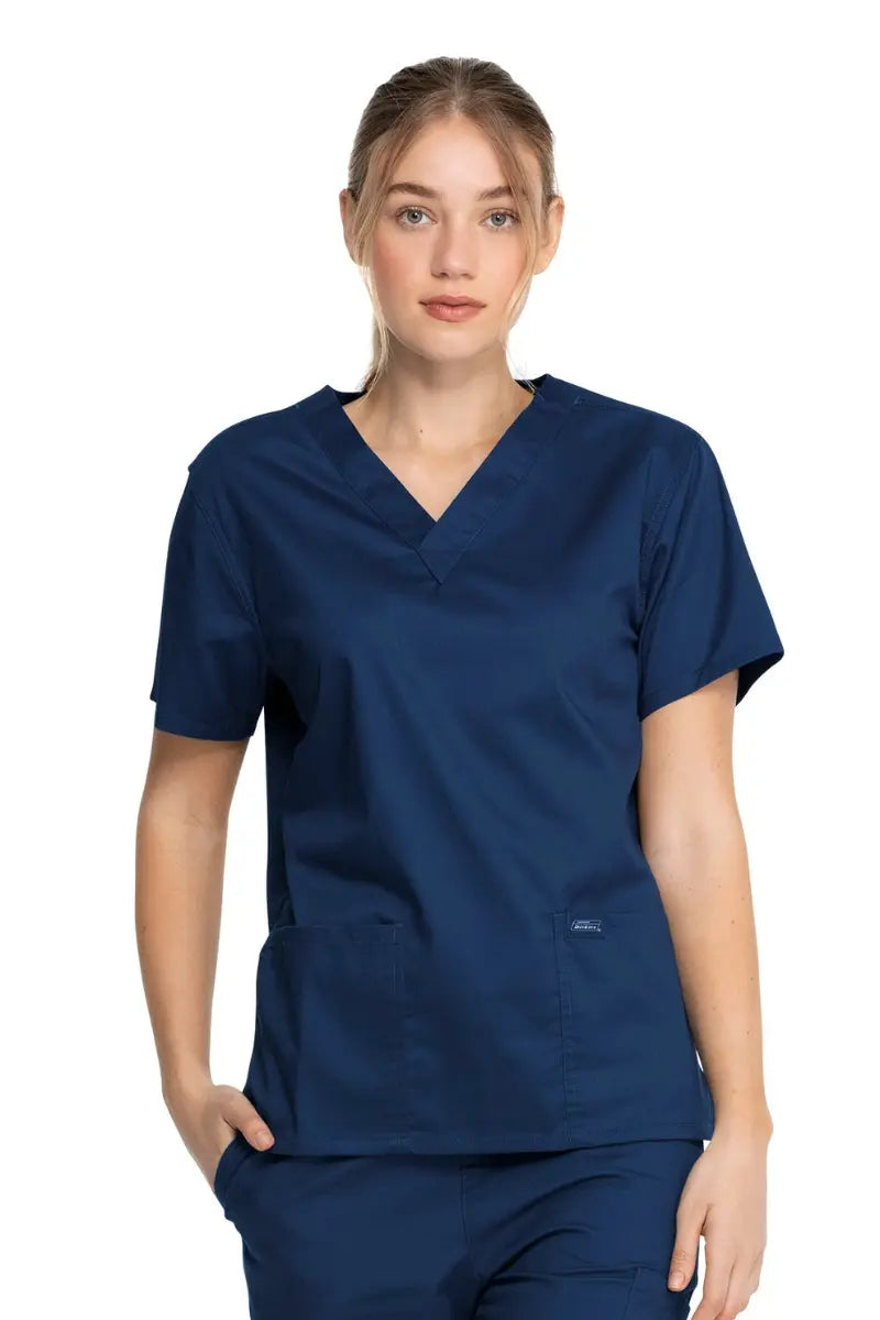 A young female Physician's Assistant wearing a Dickies Industrial Unisex V-Neck Scrub Top in Navy Blue size XXS featuring short sleeves.