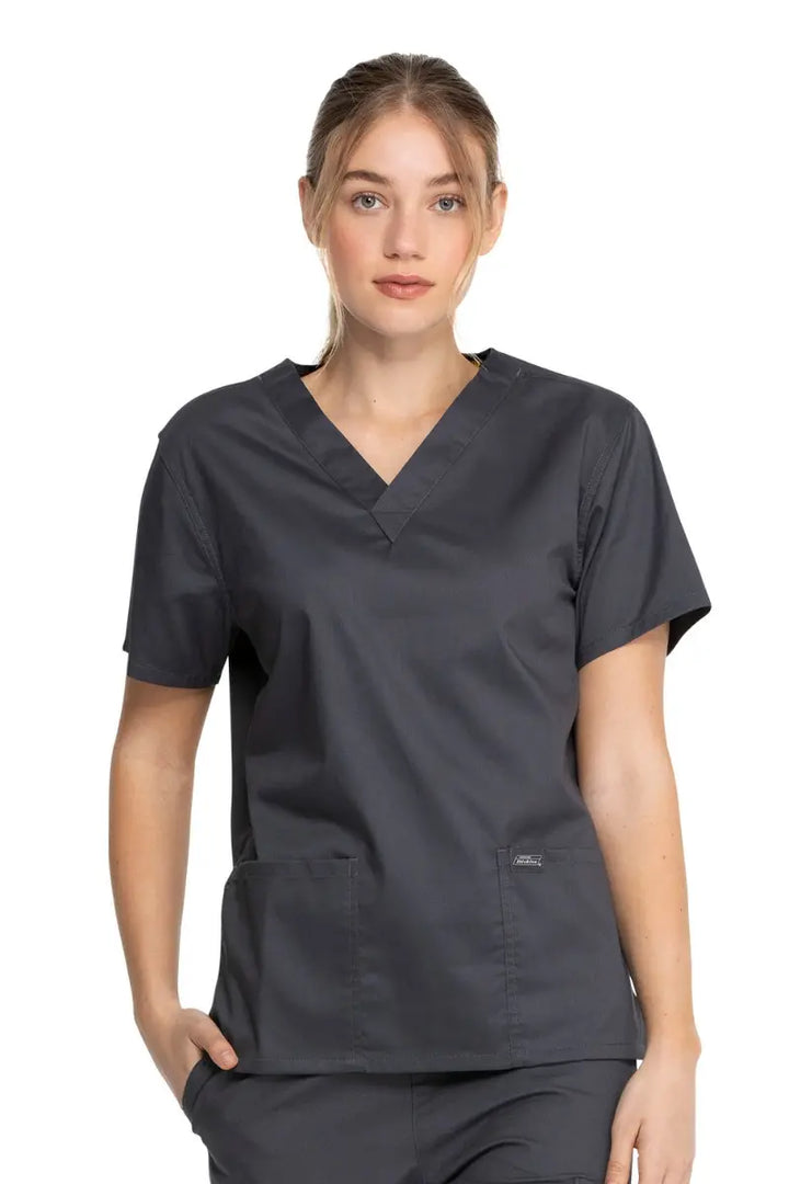 A young female Radiologic Technologist wearing a Dickies Industrial Unisex V-Neck Scrub Top in Pewter size XXS featuring short sleeves.