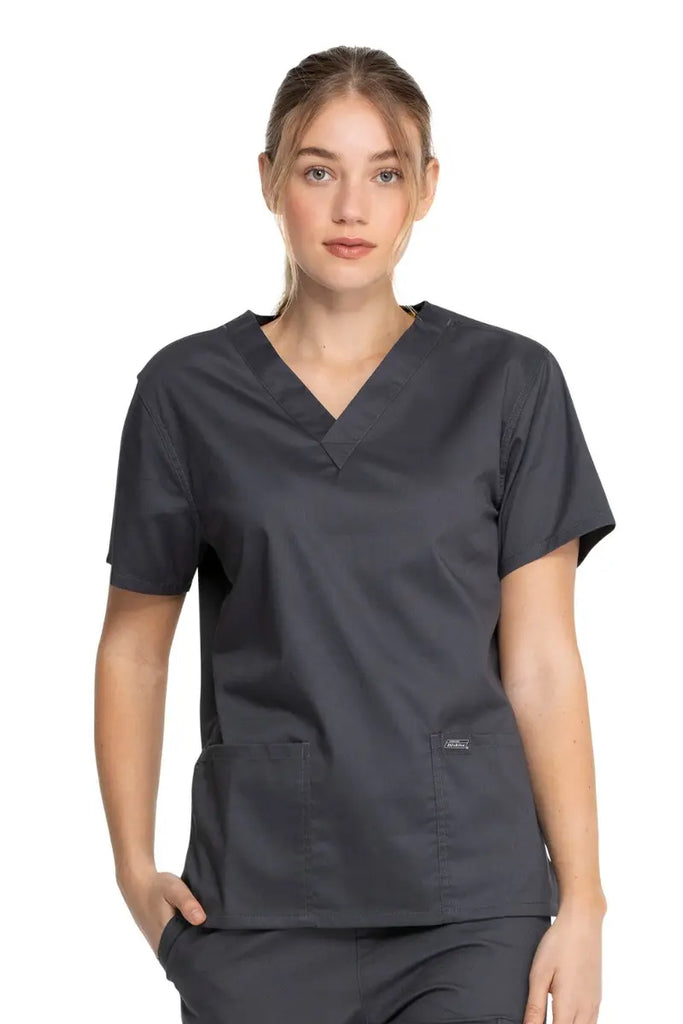 A young female Radiologic Technologist wearing a Dickies Industrial Unisex V-Neck Scrub Top in Pewter size XXS featuring short sleeves.