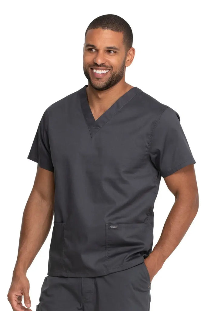 A young male Phlebotomy Technician wearing a Dickies Industrial Unisex V-Neck Scrub Top in Pewter size 2XL featuring two front patch pockets.