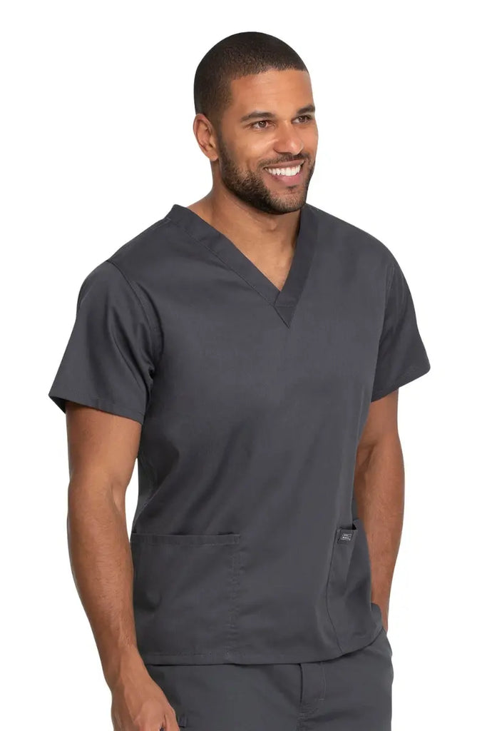 A male Medical Technician wearing a Dickies Industrial Unisex V-Neck Scrub Top in Pewter size 4XL featuring reinforced seams at stress points to provide extra strength and prevent tearing.