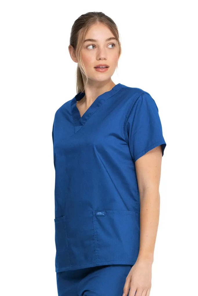 A young female Nurse Practitioner wearing a Dickies Industrial Unisex V-Neck Scrub Top in Royal Blue size XS featuring a flattering fit that ensures a comfortable and professional fit for men and women.