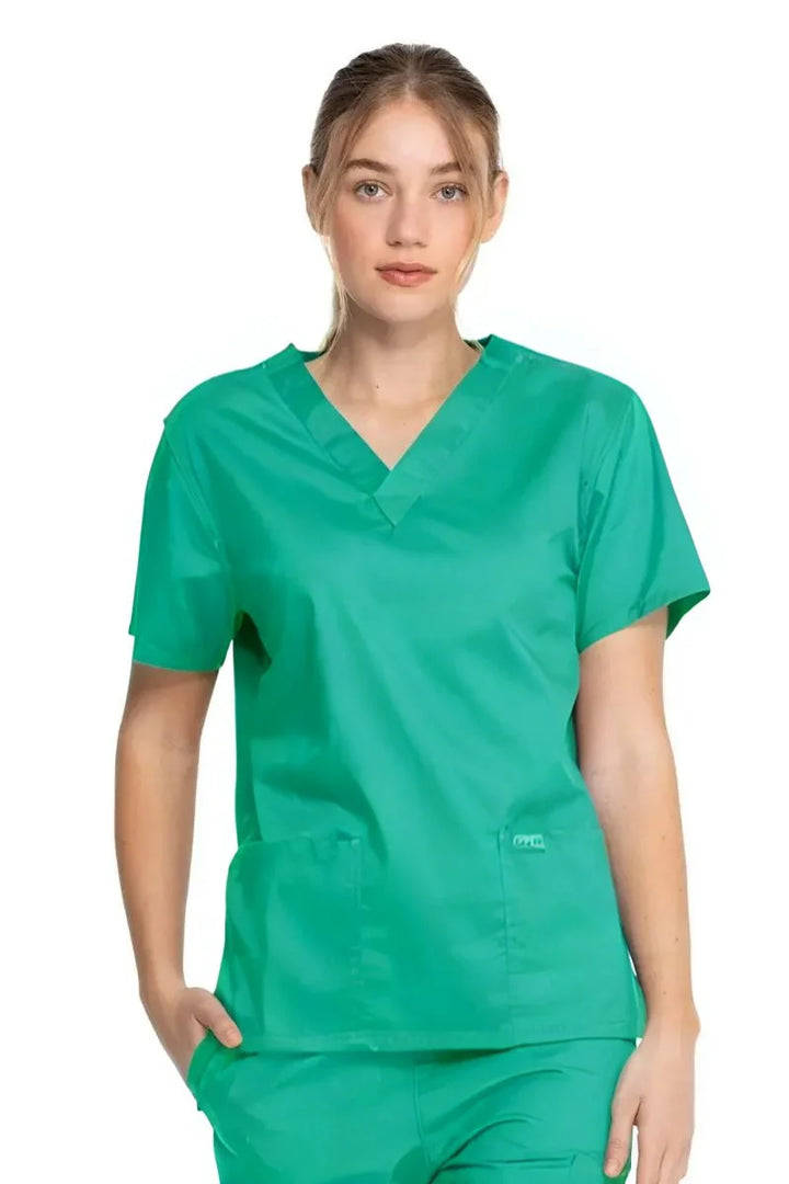 A young female Surgical Assistant wearing a Dickies Industrial Unisex V-Neck Scrub Top in Surgical Green size XXS featuring short sleeves.