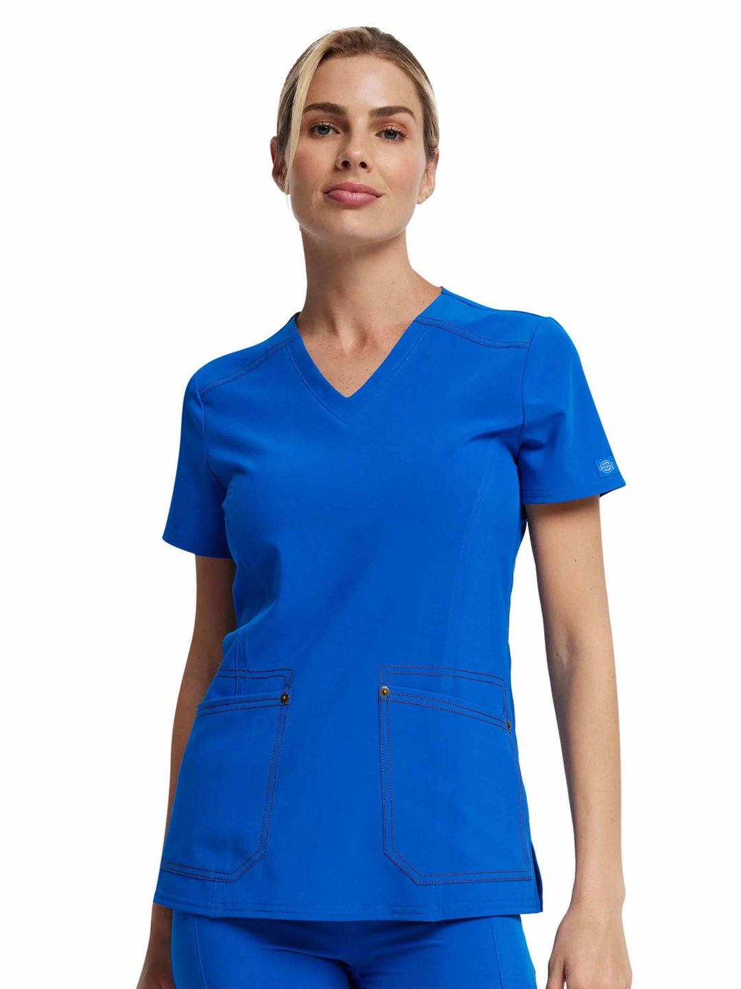 A young female Doctor wearing a Dickies Riveting Women's V-neck Scrub Top in Royal Blue featuring two front patch pockets.