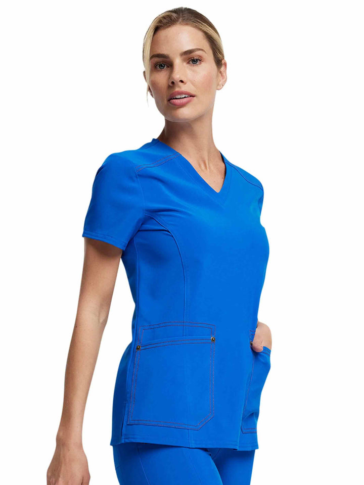 A young female Registered Nurse wearing Dickies Riveting Women's V-neck Scrub Top in Royal blue featuring a curved hem and side slits.