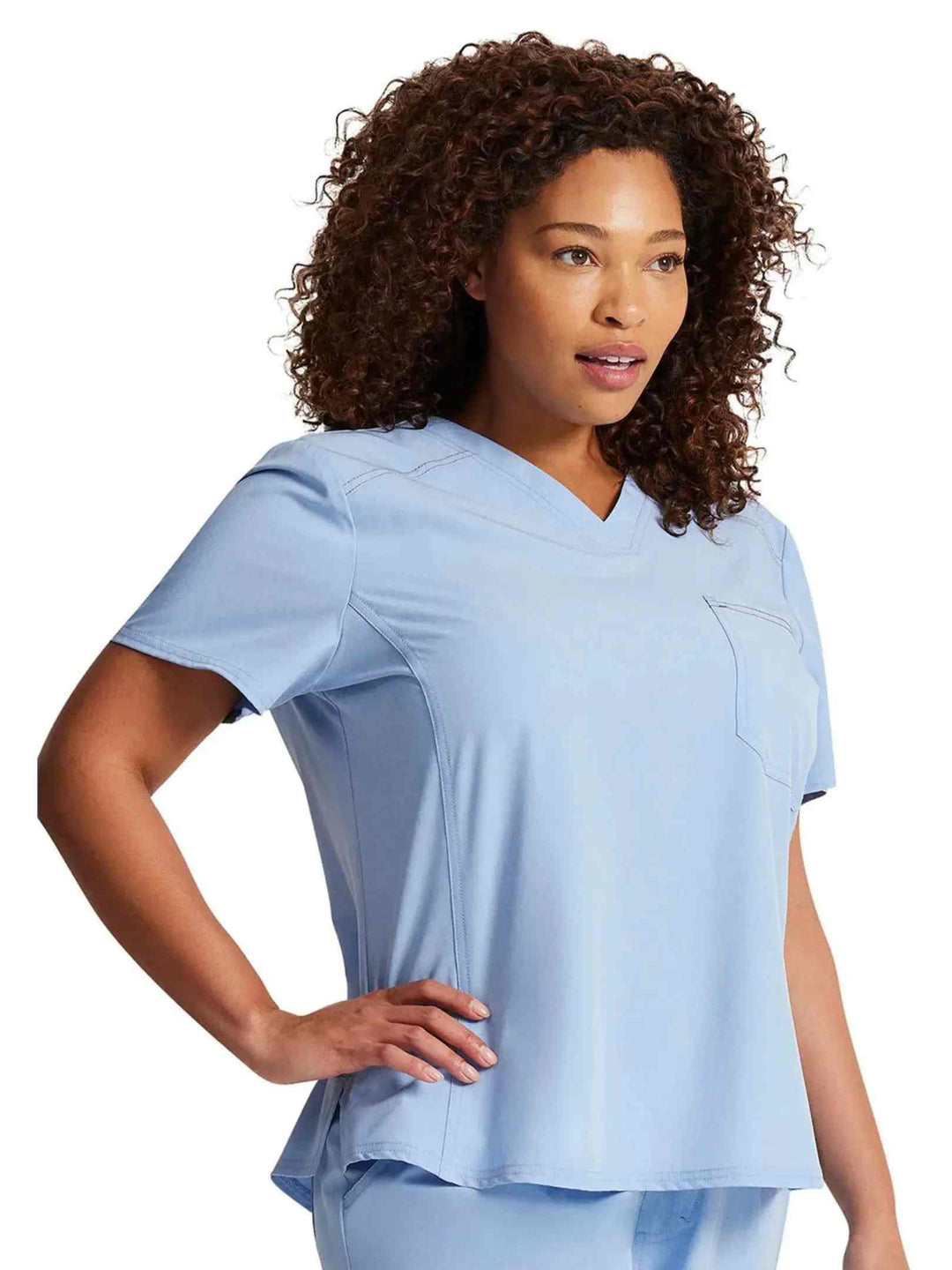 A look at the left side of the Dickies Riveting Women's Tuckable V-neck Scrub Top in Light Chambray featuring stylish seaming throughout.