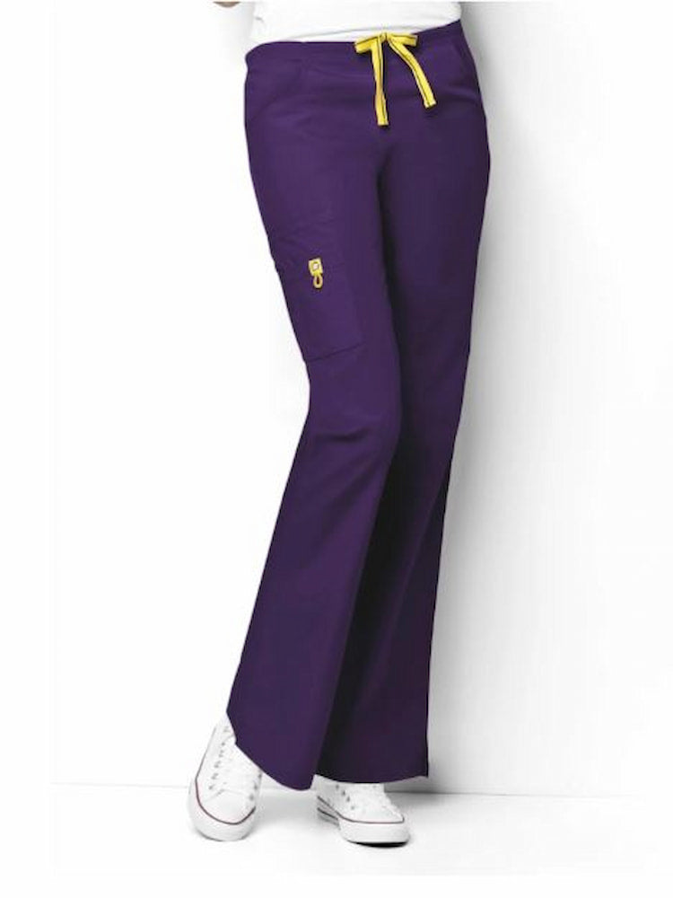 A young female Nurse Practitioner wearing a WonderWink Origins Women's Romeo Cargo Scrub Pant in Eggplant size XS petite featuring 2 front slash pockets.