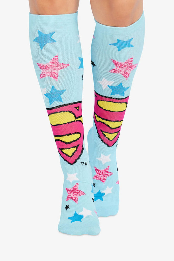 The front of the Cherokee Women's Printed Support Socks in ""Flying Hero" featuring the Supergirl emblem on a light blue background.