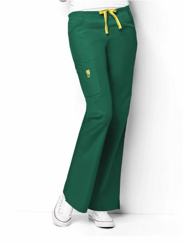 A young female Lab Tech wearing a WonderWink Origins Women's Romeo Cargo Scrub Pant in Hunter Green size XXS featuring 1 right cargo WonderWink signature triple pocket with yellow bungee ID loop.