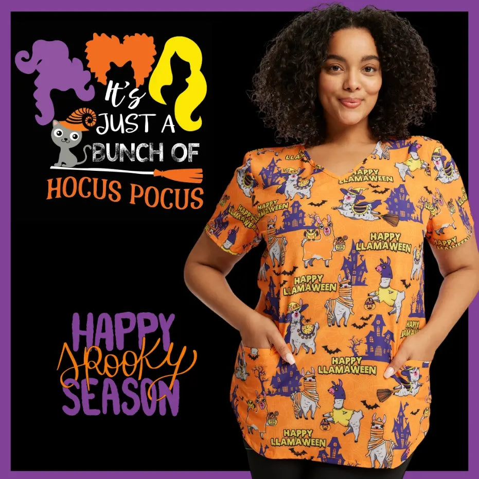 A young pediatric nurse is wearing a Halloween-themed print scrub top from Scrub Pro Uniforms on a black, purple, and orange background with text stating "Happy Spooky Season."