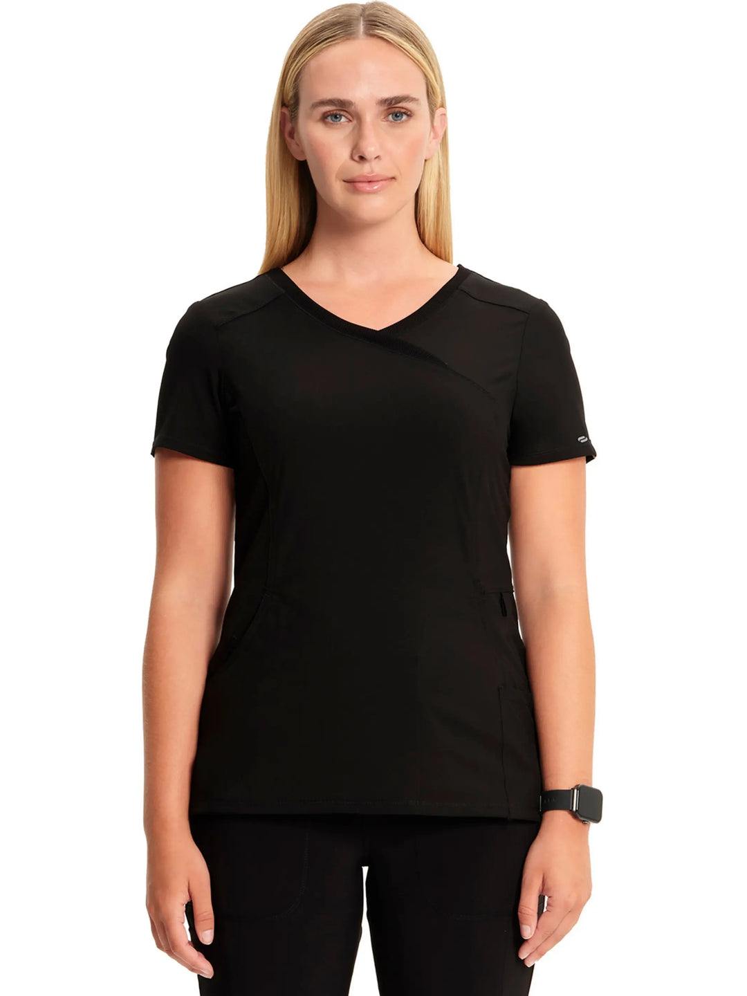 A young female EMT displaying the front of the Infinity Women's Mock Wrap Antimicrobial Scrub Top in Black on a white background.