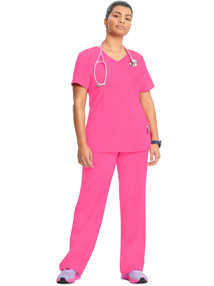 A look at a nurse wearing an Infinity Mock Wrap Scrub Top and an Infinity Women's Mid-Rise Scrub Jogger in Carmine Pink on a white background.