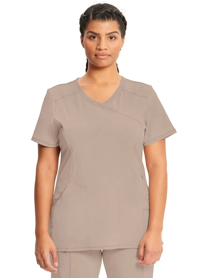 A young female Healthcare Professional displaying the front of the Infinity Women's Mock Wrap Antimicrobial Scrub Top in Khaki on a white background.