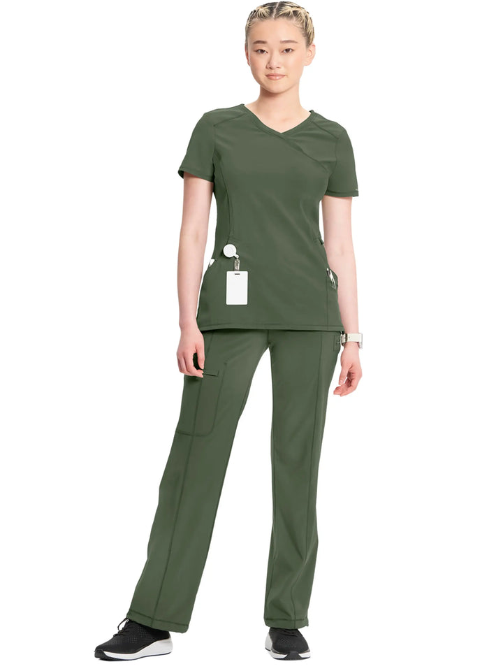 A full body shot of a nurse wearing the Infinity Women's Mock Wrap Scrub Top and Infinity Women's Mid-Rise Scrub Jogger in Olive Green on a white background.