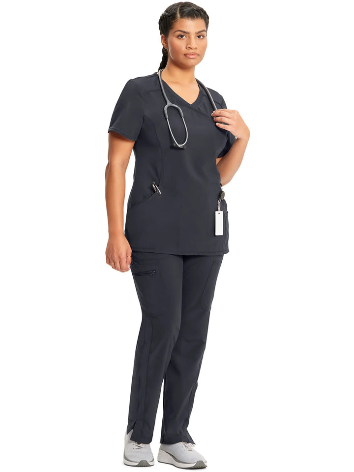 A look at a nurse wearing an Infinity Mock Wrap Scrub Top and an Infinity Women's Mid-Rise Scrub Jogger in Pewter on a white background.