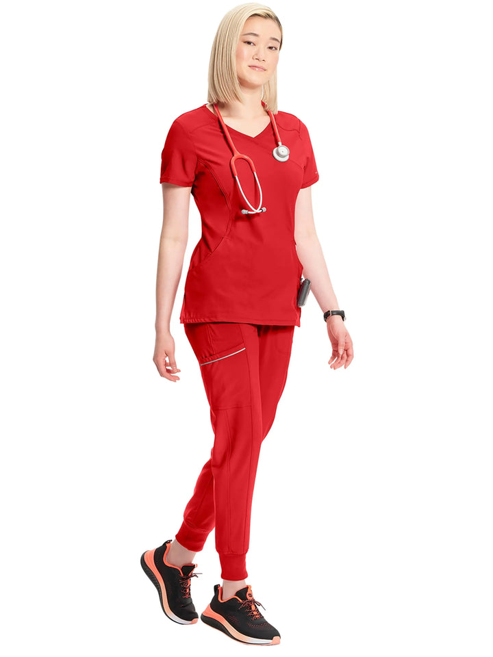 A look at a nurse wearing an Infinity Mock Wrap Scrub Top and an Infinity Women's Mid-Rise Scrub Jogger in Red on a white background.