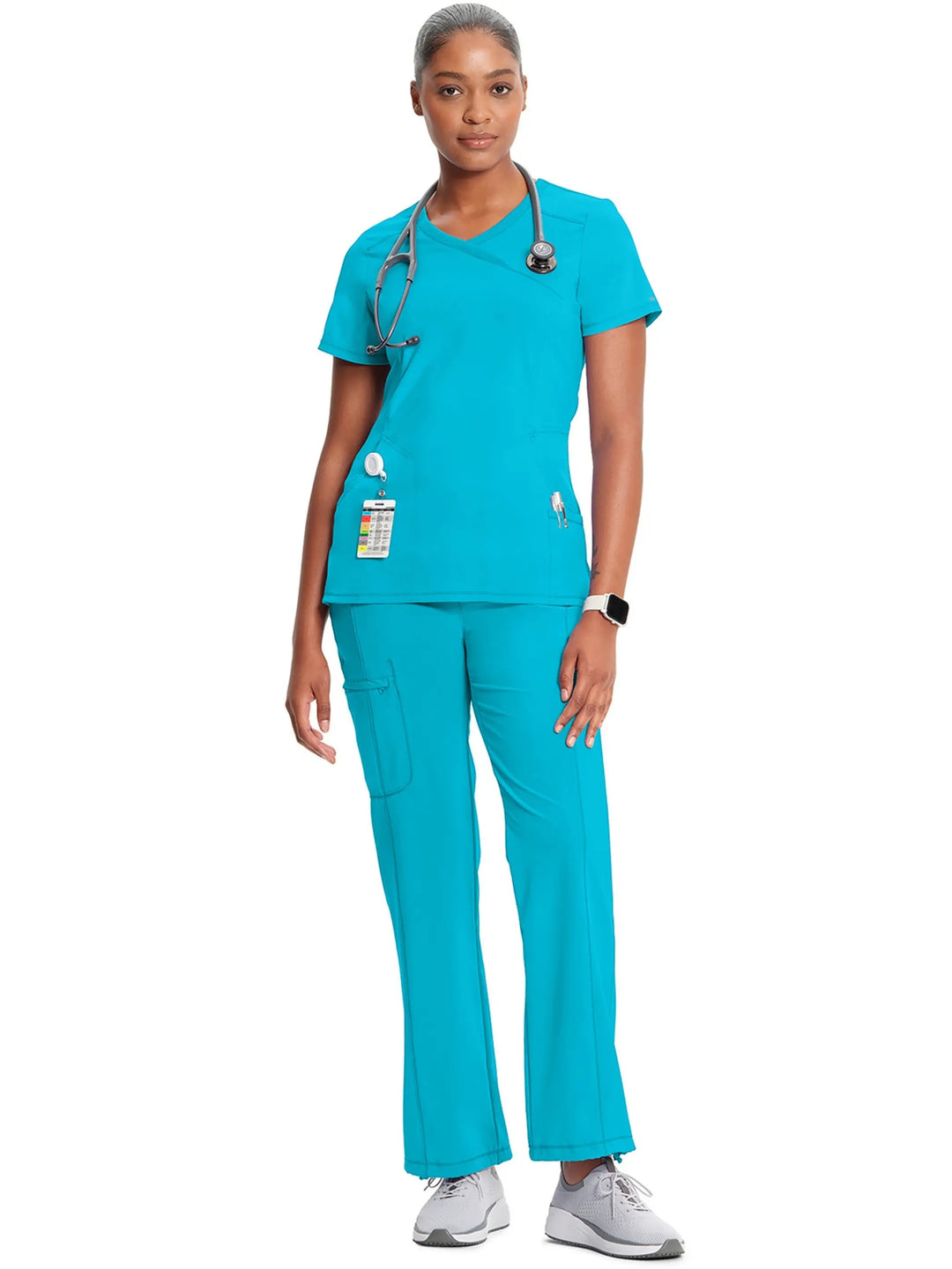 A look at a nurse wearing an Infinity Mock Wrap Scrub Top and an Infinity Women's Mid-Rise Scrub Jogger in Turquoise Blue on a white background.