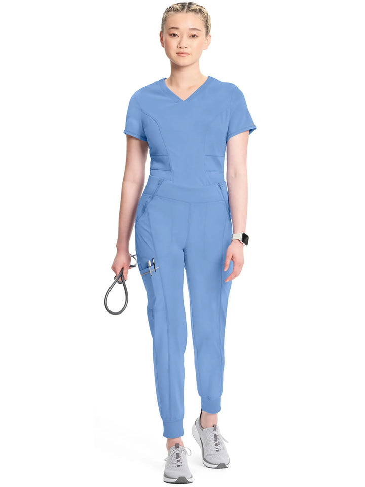 A full body look at the Infinity Women's Mid-Rise Tapered Scrub Jogger in Ceil Blue featuring ankle cuffs and an antimicrobial fabric.