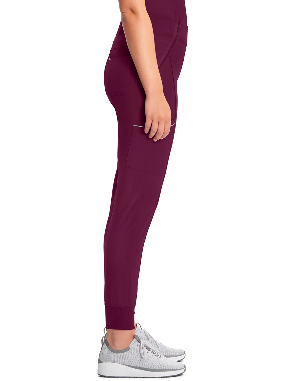 A look at the side of the Infinity Women's Mid-Rise Tapered Scrub Jogger in Wine size medium featuring a cargo zipper pocket on the wearer's right side. 