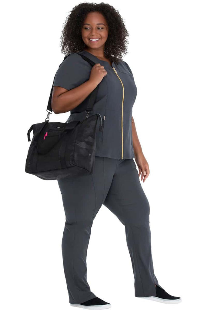 A young female Nurse Practitioner sporting a HeartSoul Madison Duffel Bag in "Black Camo" featuring an adjustable removable shoulder strap.