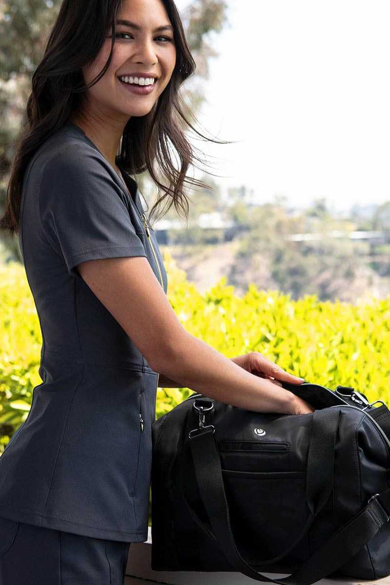 A young female Nursing Assistant packing her HeartSoul Madison Duffel bag in "Black Camo. Features include interior elastic straps to store instruments.
