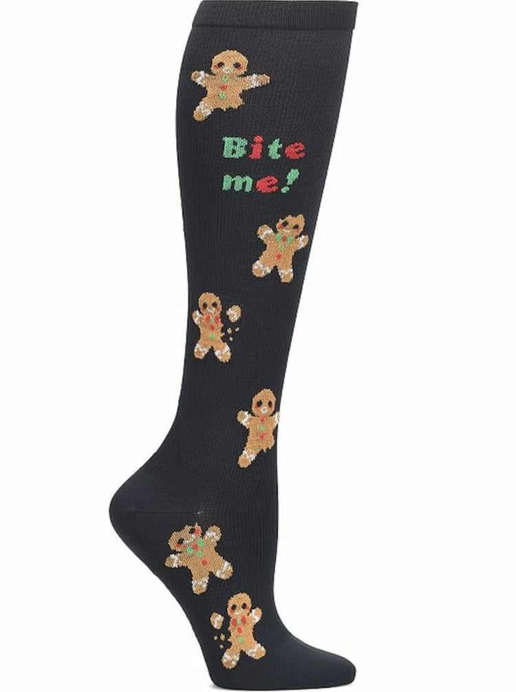 A pair of Women's Compression Socks from NurseMates in the Bite Me Print featuring a unique Christmas themed print featuring gingerbread men on a black background with the text "Bite Me!" scattered throughout.