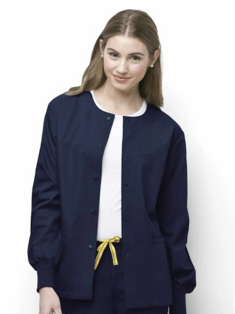 A young female Registered Nurse wearing a WonderWink Origins Delta Unisex Snap Front Jacket in Navy size XL featuring a total of 5 pockets.