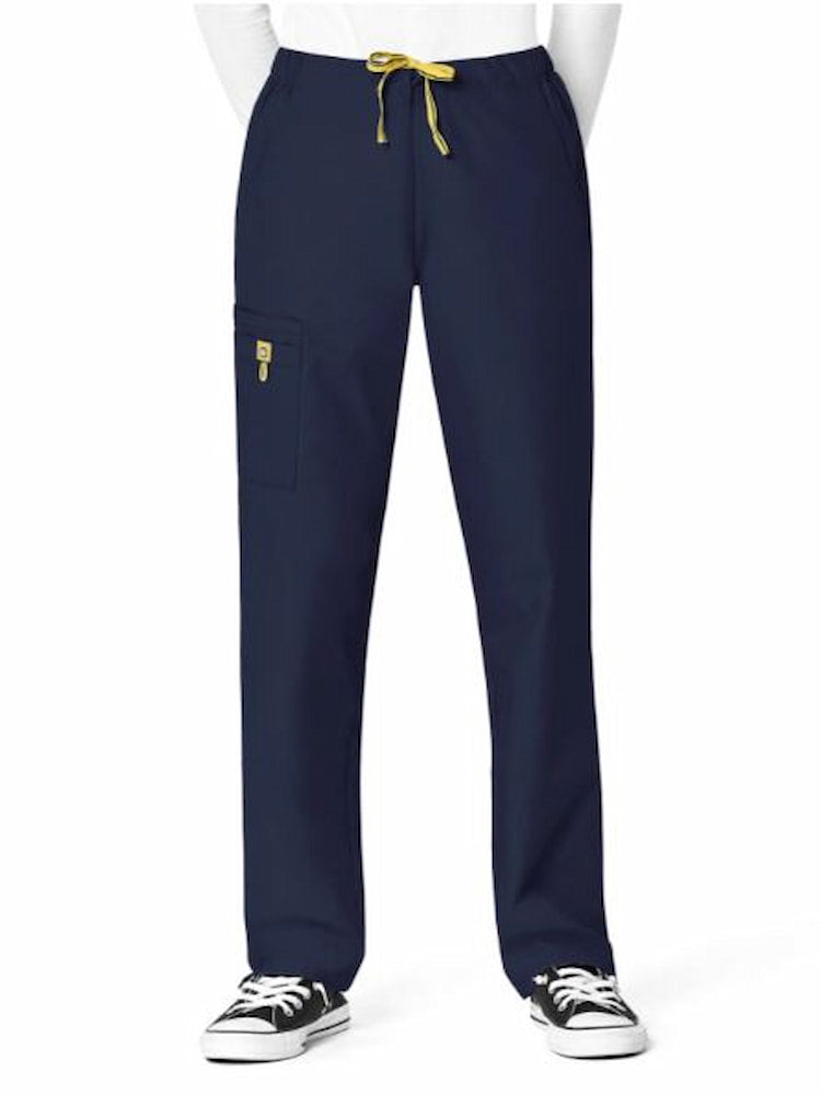 A young female Physiian's Assistant wearing a WonderWink Origins Women's Slim Leg Cargo Scrub Pant in Navy size Small Petite featuring a modern fit.