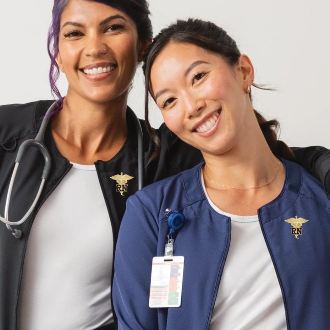 Two young women displaying some of the available Nurse Pins at Scrub Pro.