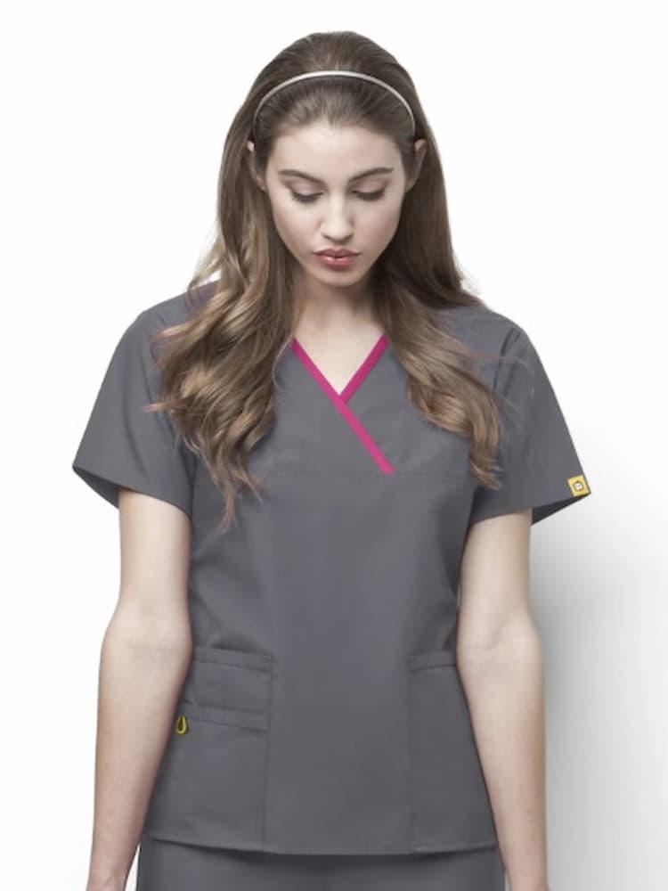 A young female Registered Nurse wearing a WonderWink Origins Women's Charlie Y-neck Scrub Top in Pewter size XL featuring a stylish mock wrap neckline, short sleeves and a total of 5 pockets.