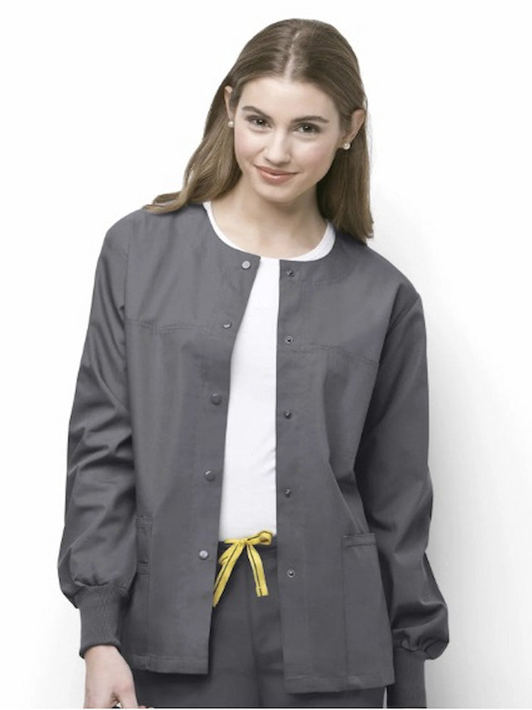 A young female LPN wearing a WonderWink Origins Delta Unisex Snap Front Scrub Jacket in Pewter size 2XL featuring rib knit cuffs.