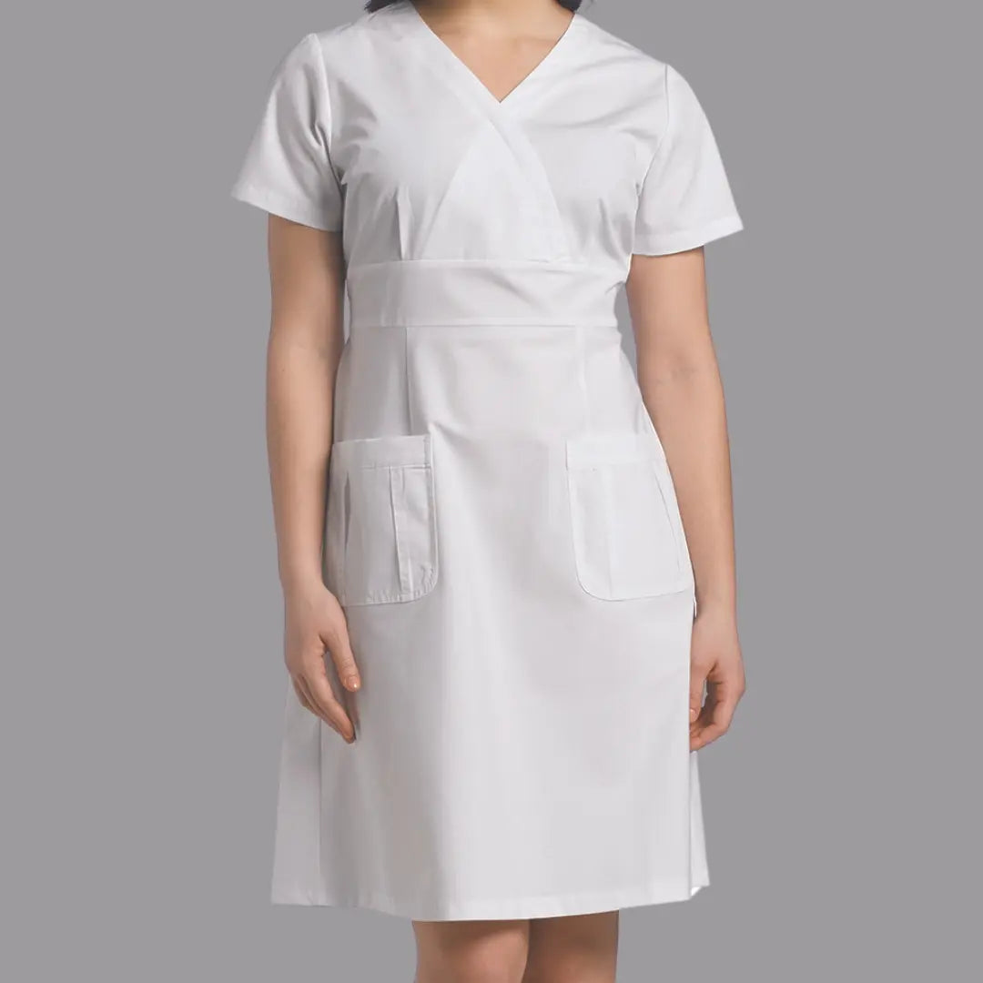 A young female nurse showcasing one of Scrub Pros available women's plus-size scrub dresses on a grey background.