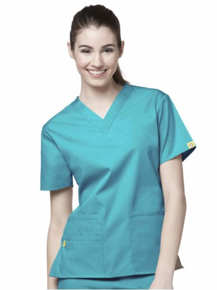 An image of a young female Dental Hygienist wearing a WonderWink Origins Women's Bravo Scrub Top in Real Teal featuring a total of 5 pockets. 