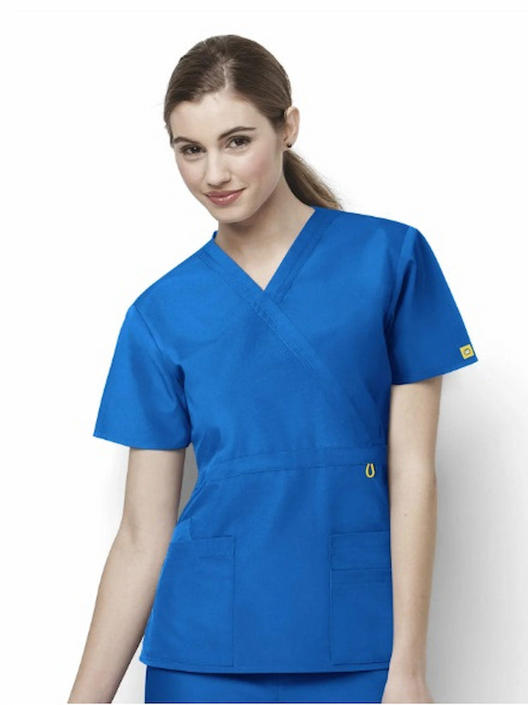 A young female Physical Therapist wearing a WonderWink Women's Origins Women's Fashion Waist Scrub Top in Royal size 3XL featuring 4 total pockets.