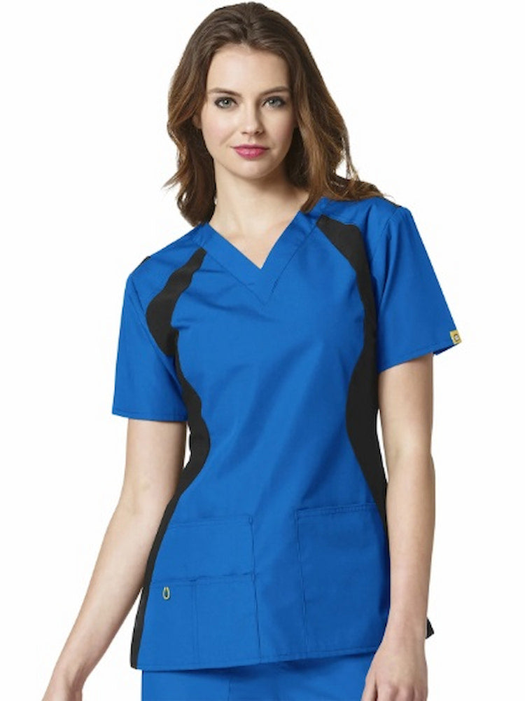 A young female Physical therapist's Assistant wearing a WonderWink Origins Lima Knit Panel Scrub Top in Royal size Large featuring contour knit side panels for a flattering fit.