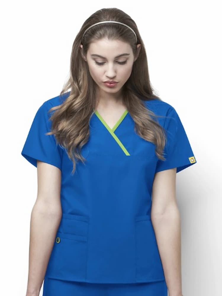 A young female Physical Therapist wearing a WonderWink Origins Women's Charlie Y-neck Scrub Top in Royal size 3XL featuring shot sleeves & vented sides.