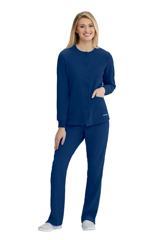 A full body shot of a young female Nurse Practitioner wearing a Skechers scrub uniform in navy on a white background.