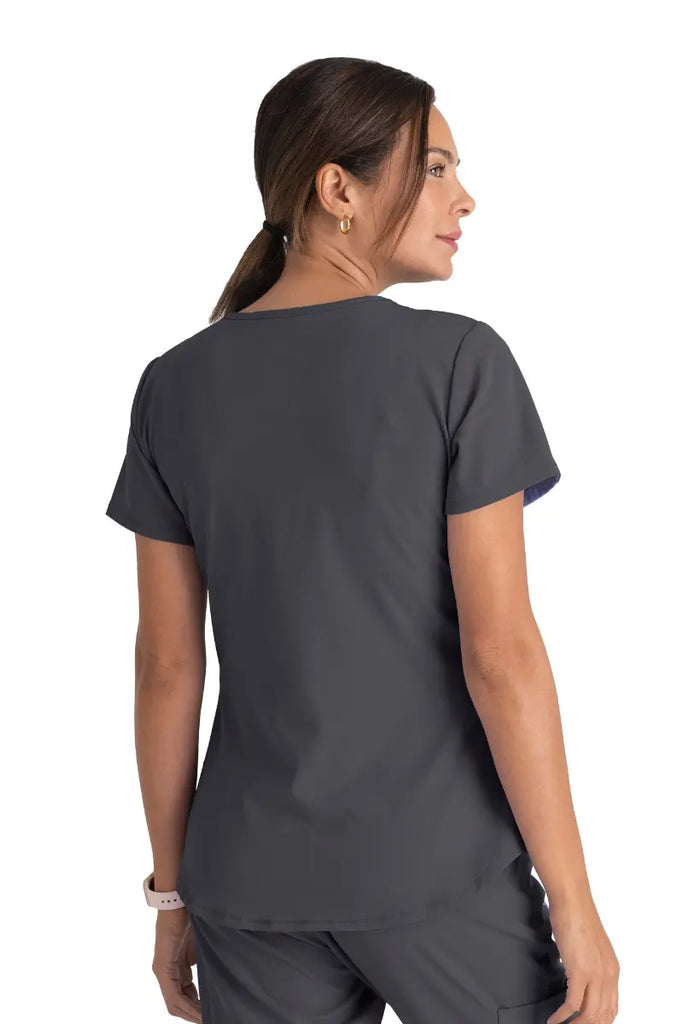 A young female Radiology Tech wearing a Skechers Women's Breeze V-neck Scrub Top in Pewter size Medium featuring a center back length 25.5".