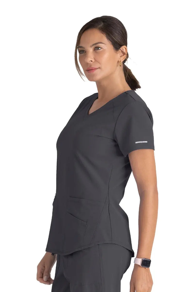 A young female Registered Nurse wearing a Skechers Women's Breeze V-neck Scrub Top in Pewter size XS featuring a modern fit.