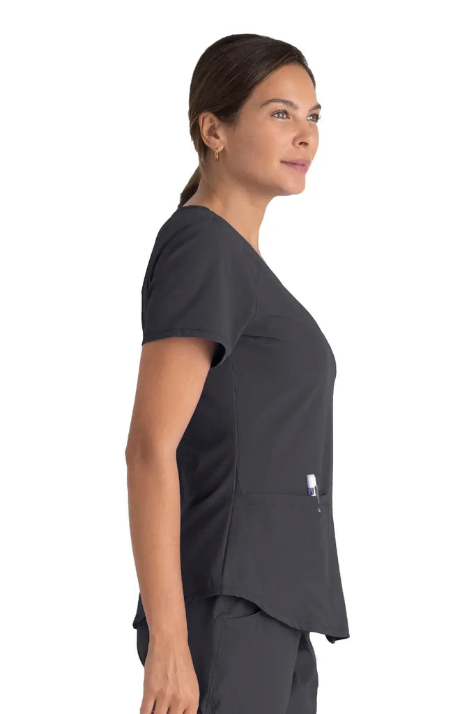 A young female Pharmacy Technician wearing a Skechers Women's Breeze V-neck Scrub Top in Pewter featuring a shaped hem.