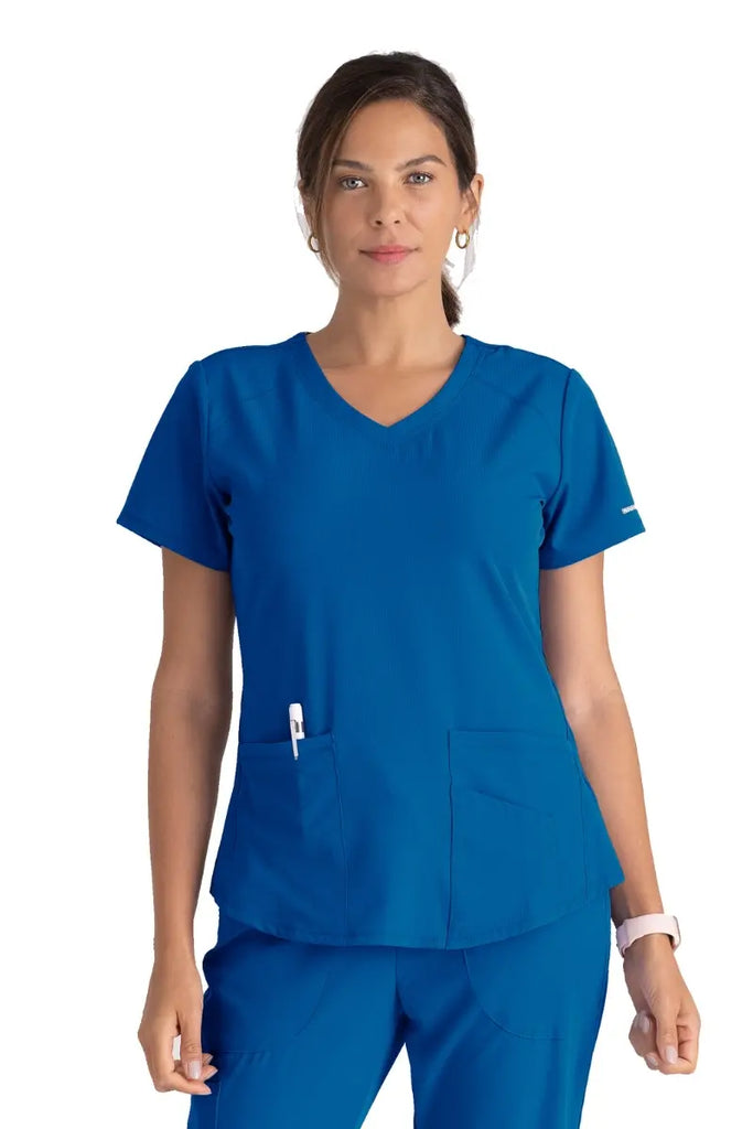 A young female Physical Therapist wearing a Women's Breeze V-neck Scrub Top from Skechers in Royal featuring a modern fit.