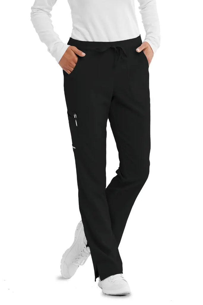 A female Home Health Aide wearing a Skechers women's Reliance Cargo Scrub Pant in black size small featuring 2 front patch pockets.