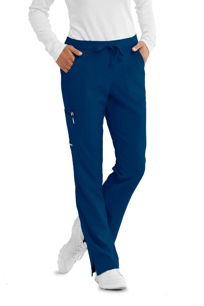 A young Female Radiologist wearing a pair of Skechers women's Reliance Cargo Scrub Pants in navy size medium tall featuring a shaped flare leg.